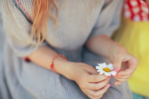 Frau sitzt ruhig da und zupft Blütenblätter von einem Gänseblümchen
